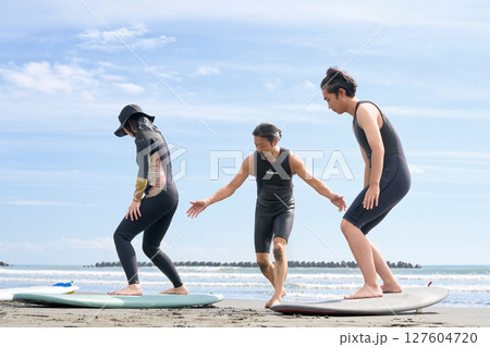ビーチでサーフィン体験を受ける若者と指導者　サーフィンスクール　イメージ 127604720
