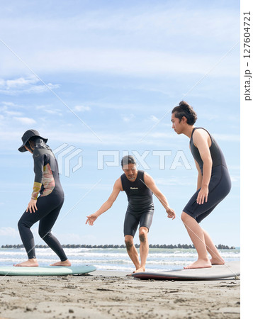 ビーチでサーフィン体験を受ける若者と指導者　サーフィンスクール　イメージ 127604721