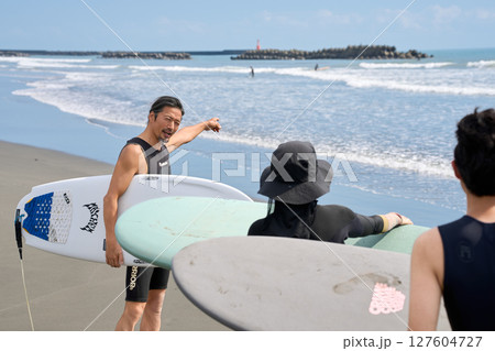 サーフィン前に海の状況を確認するインストラクターと参加者 127604727