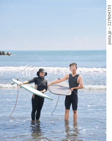 海でサーフィンを体験する女性と若い男性のツーショット 127604733