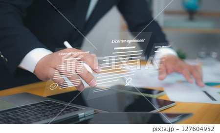 License agreement, featuring digital checkmarks and signatures. Symbolizes efficient online contract management and modern legal agreements. Businessman uses a stylus to interact with documents. License agreement, featuring digital checkmarks and signatures. Symbolizes efficient online contract management and modern legal agreements. Businessman uses a stylus to interact with documents. 127604952
