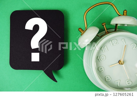 Question mark text on speech bubble with alarm clock on green background 127605261