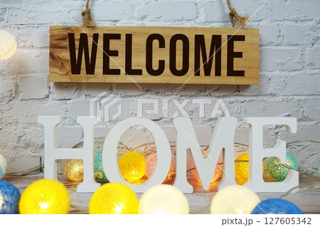 Welcome Home alphabet letters with wooden signboard hanging on white brick wall background 127605342
