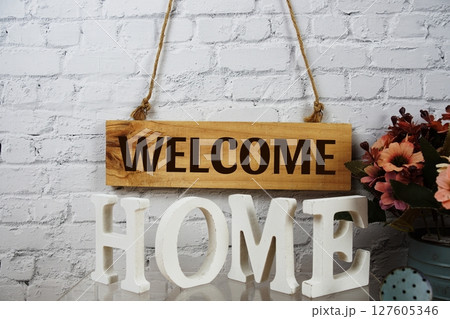 Welcome Home alphabet letters with wooden signboard hanging on white brick wall background 127605346