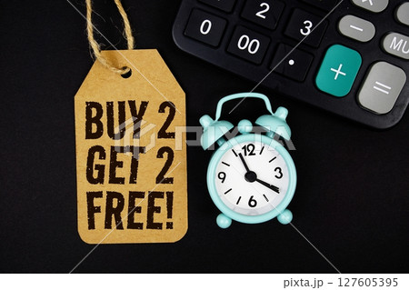 Buy 2 Get 2 Free! text on price tag with alarm clock and calculator on black background Buy 2 Get 2 Free! text on price tag with alarm clock and calculator on black background 127605395