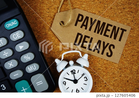 Payment Delays text on price tag with alarm clock and calculator on cork board background 127605406