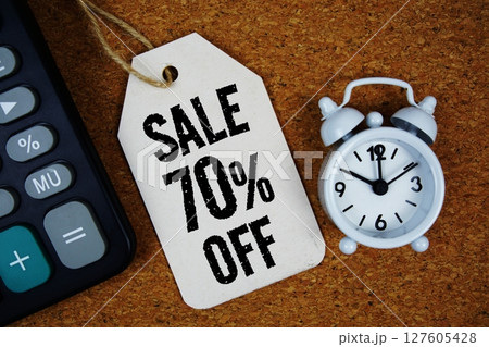 Sale 70% Off text on price tag with alarm clock and calculator on cork board background Sale 70% Off text on price tag with alarm clock and calculator on cork board background 127605428