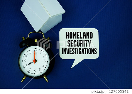 HSI Homeland Security Investigations  text with alarm clock and house model top view on blue background 127605541