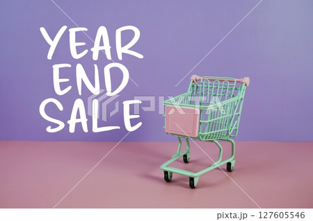 Year End Sale text with trolley shopping cart on purple and pink geometric background 127605546