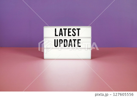 Latest Update text on LED lightbox on purple and pink geometric background Latest Update text on LED lightbox on purple and pink geometric background 127605556