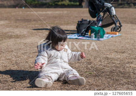 【相模原市立麻溝公園の芝生広場で遊ぶ1歳児　座る】 127605655