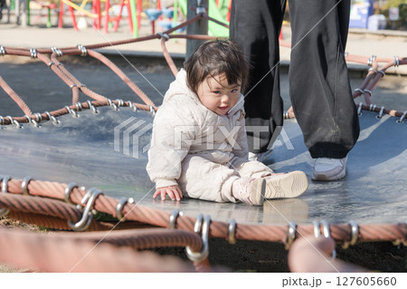 【相模原市立麻溝公園の子どもの広場のトランポリンでママと遊ぶ1歳児】 127605660