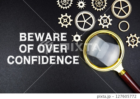 Beware Of Over Confidence text message with magnifying glass on black background 127605772