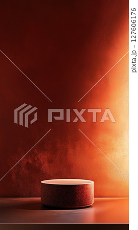 Minimalist display featuring a cylindrical object on a wooden surface against a warm backdrop 127606176