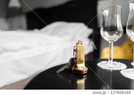 Experience the luxury of a sophisticated hotel room complete with a key and elegant wine glasses Experience the luxury of a sophisticated hotel room complete with a key and elegant wine glasses 127606288