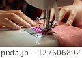 A woman sews on a sewing machine 127606892
