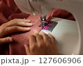 A woman sews on a sewing machine 127606906