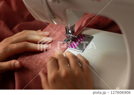 A woman sews on a sewing machine 127606906