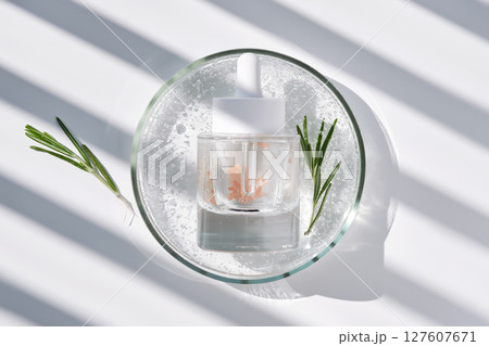 A bottle of rosemary serum in a petri dish. A bottle of rosemary serum in a petri dish. 127607671