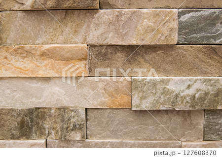 Beautiful beige structural stone wall of the ancient building consists of small bricks. Beautiful beige structural stone wall of the ancient building consists of small bricks. 127608370