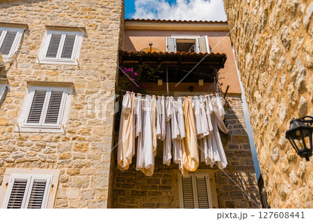 Sunlit stone houses with drying laundry in a Mediterranean old town. Daily life, authentic atmosphere and summer street scene Sunlit stone houses with drying laundry in a Mediterranean old town. Daily life, authentic atmosphere and summer street scene 127608441