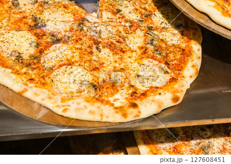 Close-up of freshly baked pizza with melted cheese and herbs. Italian street food, fast casual dining and comfort meal with traditional flavors. 127608451