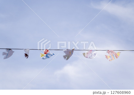 A Stunning Display of Colorful Paper Birds Elegantly Hanging Against a Bright Blue Sky 127608960