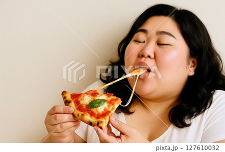 チーズが伸びるピザを頬張るぽっちゃり女性｜食欲・幸せな食事シーン・ファストフードイメージ 127610032