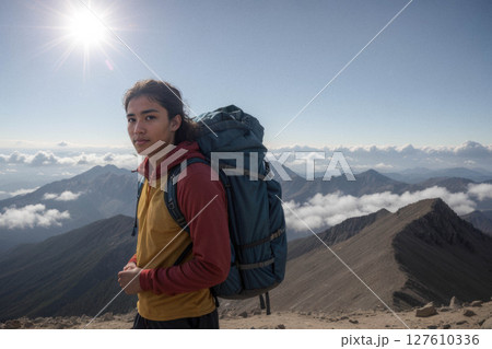 Young Man Hiking on Mountain Peak with Backpack 127610336