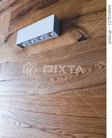 Elongated white plastic lamp on a wooden wall. Minimalism style Elongated white plastic lamp on a wooden wall. Minimalism style 127610604