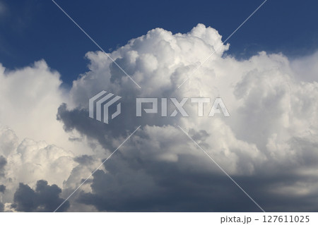 Dramatic clouds illuminated by sunlight against blue sky 127611025