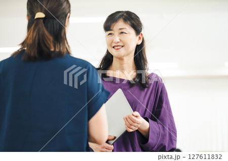 同僚と楽しく話す50代のキャリアウーマン 同僚と楽しく話す50代のキャリアウーマン 127611832