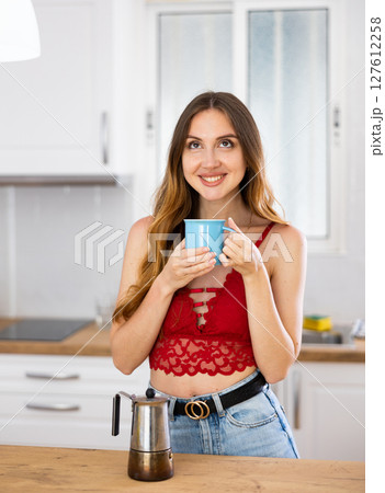 Smiling woman drinking coffee at home 127612258