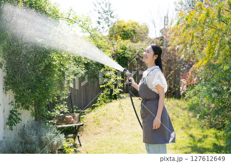 庭に水撒きをする女性 127612649