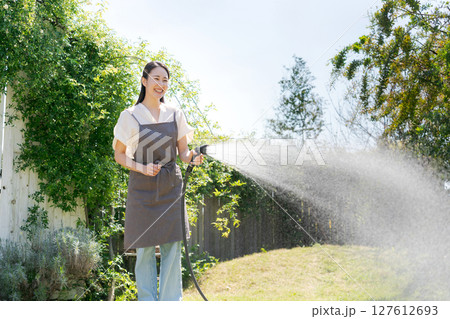 庭に水撒きをする女性 127612693