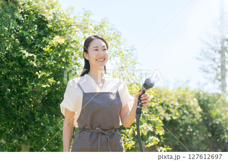 庭に水撒きをする女性 127612697