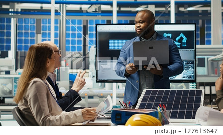 Teamworking factory colleagues researching new photovoltaics materials. Team of solar panel manufacturing plant researchers developing new solar energy systems prototypes, camera B Teamworking factory colleagues researching new photovoltaics materials. Team of solar panel manufacturing plant researchers developing new solar energy systems prototypes, camera B 127613647