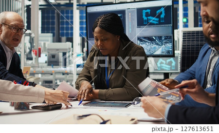 Factory management presents business models to businessmen, expanding production. Shareholders discuss integrating automation technology in industrial plant, looking at equipment options, camera A 127613651