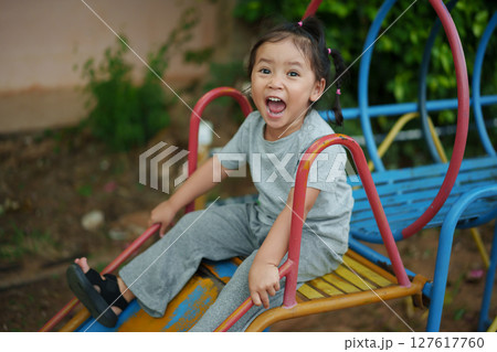 happy toddler baby girl sliding and playing at playground 127617760