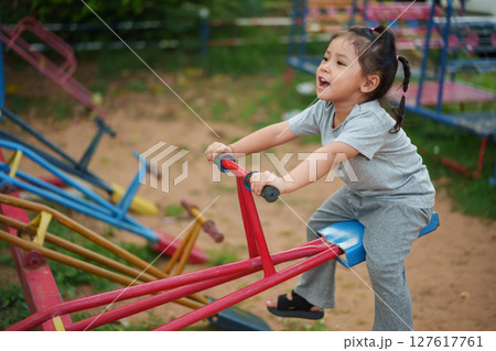 toddler girl playing seesaw in playground toddler girl playing seesaw in playground 127617761