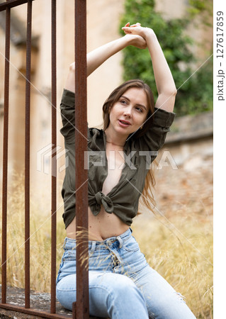 Woman in unbuttoned blouse posing near fence Woman in unbuttoned blouse posing near fence 127617859