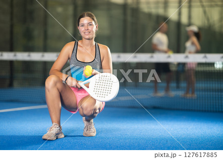 Young woman posing indoor on padel court with racket and ball Young woman posing indoor on padel court with racket and ball 127617885