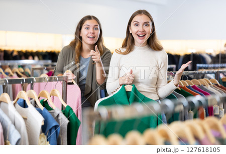 Enthusiastic young girls pointing each other to new clothes in mall Enthusiastic young girls pointing each other to new clothes in mall 127618105
