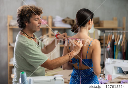 Man tailor takes measurements from female client Man tailor takes measurements from female client 127618224