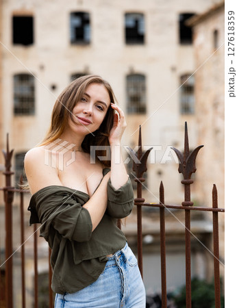 Woman in unbuttoned blouse posing near fence 127618359