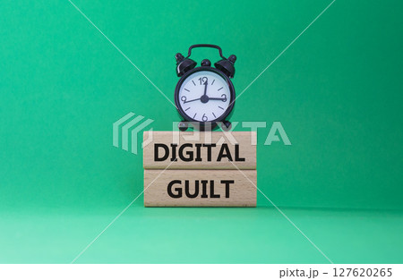 Digital Guilt symbol. Concept words Digital Guilt on wooden blocks. Beautiful green background with alarm clock. Business and Digital Guilt concept. Copy space. Digital Guilt symbol. Concept words Digital Guilt on wooden blocks. Beautiful green background with alarm clock. Business and Digital Guilt concept. Copy space. 127620265