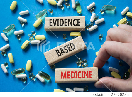 Evidence Based Medicine symbol. Concept word Evidence Based Medicine on wooden blocks. Doctor Hand. Beautiful blue background with pills. Medicine and Evidence Based Medicine concept. Copy space Evidence Based Medicine symbol. Concept word Evidence Based Medicine on wooden blocks. Doctor Hand. Beautiful blue background with pills. Medicine and Evidence Based Medicine concept. Copy space 127620283