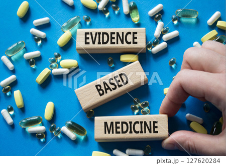Evidence Based Medicine symbol. Concept word Evidence Based Medicine on wooden blocks. Doctor Hand. Beautiful blue background with pills. Medicine and Evidence Based Medicine concept. Copy space 127620284