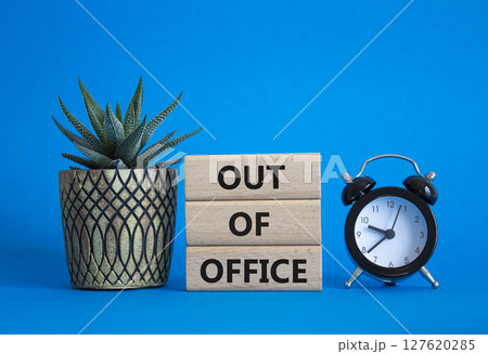 Out of Office symbol. Concept words Out of Office on wooden blocks. Beautiful blue background with succulent plant and alarm clock. Business and Out of Office concept. Copy space 127620285
