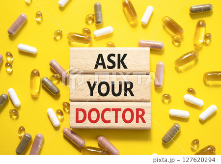 Ask Your Doctor symbol. Concept word Ask Your Doctor on wooden blocks. Beautiful yellow background with pills. Medicine and Ask Your Doctor concept. Copy space 127620294